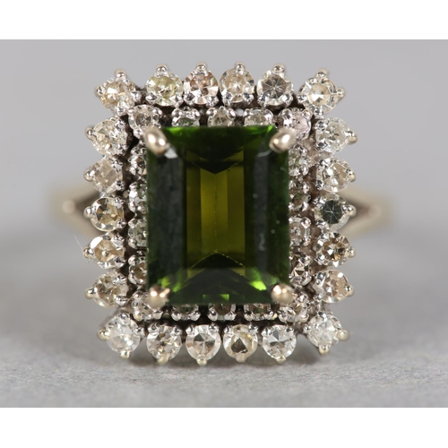 244 - A TOURMALINE AND DIAMOND CLUSTER RING c.1960, the step cut tourmaline claw set to the centre and rai... 