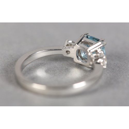 245 - AN AQUAMARINE AND DIAMOND THREE STONE RING in platinum, the square faceted aquamarine flanked by two... 