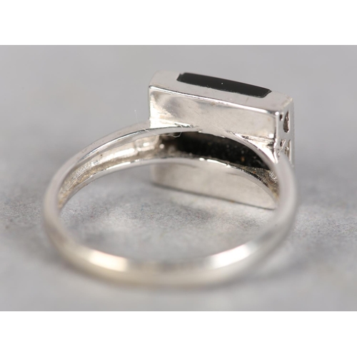 247 - AN ONYX AND DIAMOND ART DECO STYLE RING in 18ct white gold, the square onyx open seal, flanked by tw... 