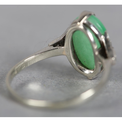 248 - A JADE AND DIAMOND DRESS RING in 18ct white gold, claw set with an oval cabochon stone flanked by si... 