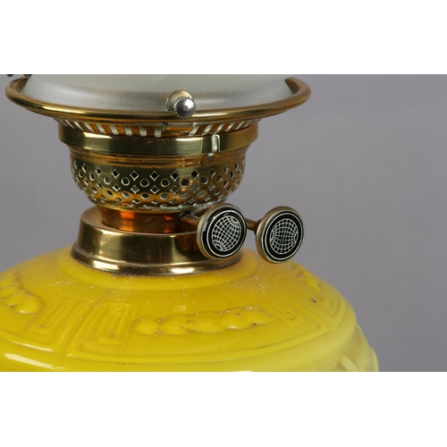 98 - A VICTORIAN BRASS OIL LAMP embossed with a band of plant forms, having a yellow tinted glass reservo... 