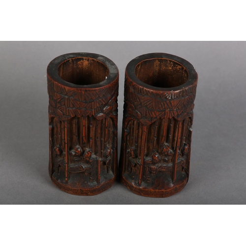 176 - A PAIR OF 19TH CENTURY BAMBOO BRUSH POTS, each carved in relief with figures amongst trees beneath a... 