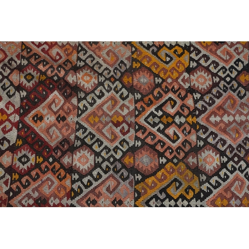 310 - A KELIM RUNNER worked in yellow, aubergine, mauve, wine, brown and ochre with a traditional geometri... 