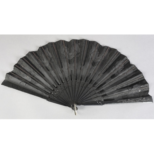 37 - C 1905/10, a wood fan with incised and clouté monture, the black gauze leaf applied with silk panels... 