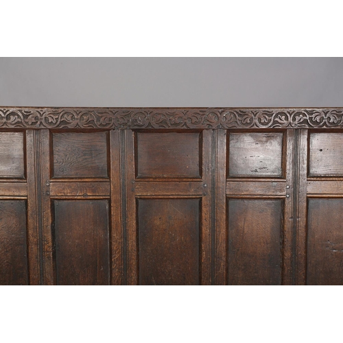 377 - AN 18TH CENTURY OAK SETTLE, the back having seven field panels, strung seat with later cushion, slab... 