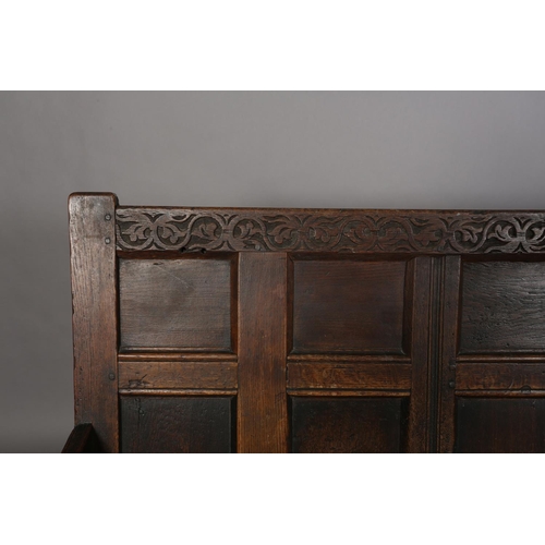 377 - AN 18TH CENTURY OAK SETTLE, the back having seven field panels, strung seat with later cushion, slab... 