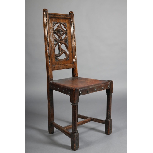 386 - A LATE 19TH CENTURY ELM HALL CHAIR, the panel back pierced with diamond and triform motifs, gauge-cu... 