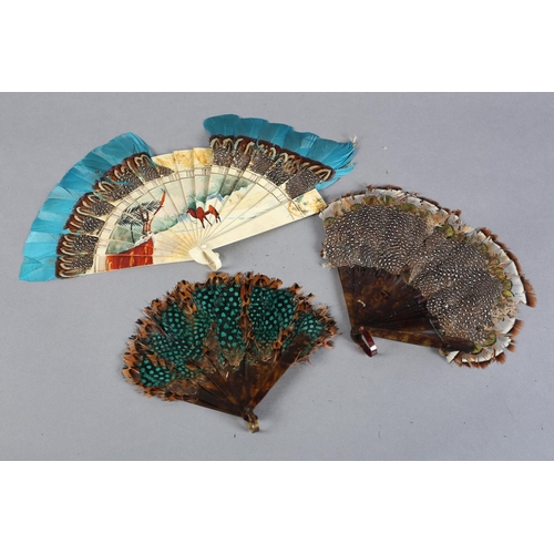 39 - Three marquetry feather fans, the first of cream celluloid, painted with s desert scene with palms a... 