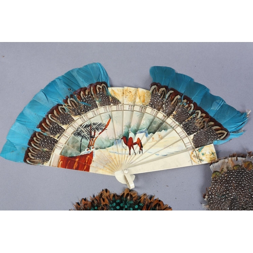 39 - Three marquetry feather fans, the first of cream celluloid, painted with s desert scene with palms a... 