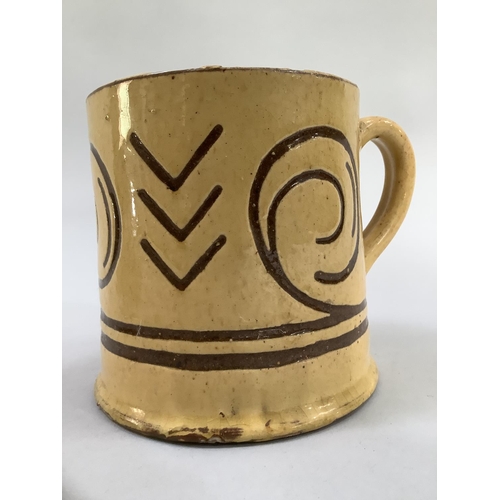 11 - A slipware cradle, 18cm long and an earlier earthenware mug, the yellow glaze incised with geometric... 