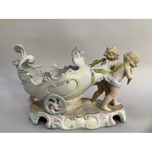 54 - A late 19th century continental china table piece modelled as cherubs pulling a chariot, oval base m... 