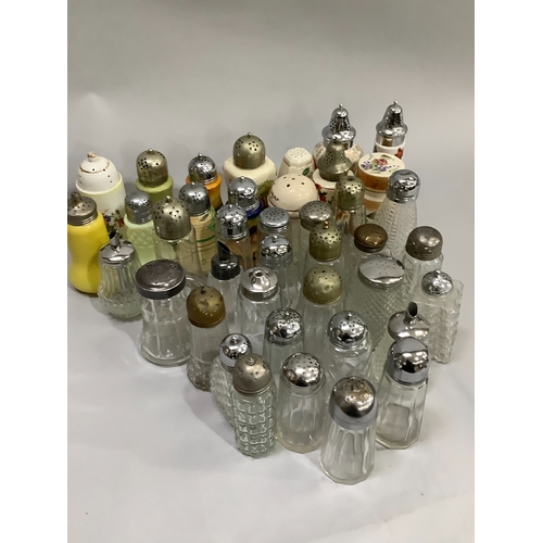 96 - A large collection of glass sugar sifters with silver plated and other tops