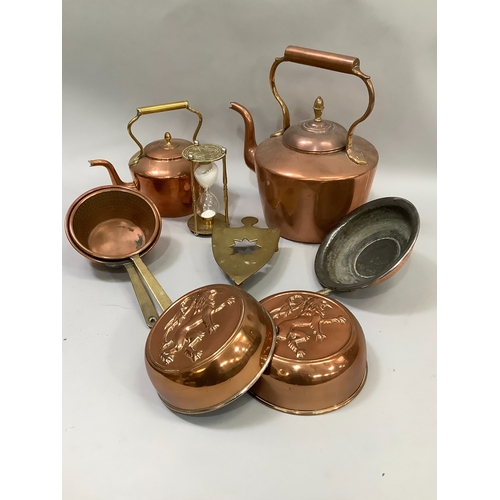 91 - A collection of copperware comprising two copper kettles, two moulds, pans, a brass trivet etc