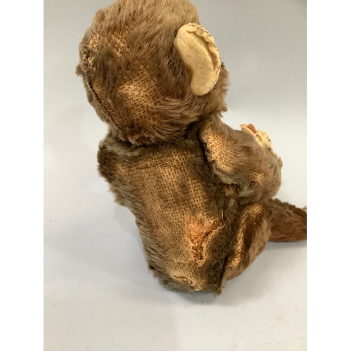 59 - A Steiff monkey with brown fur, pink face and paws, label to ear, worn condition