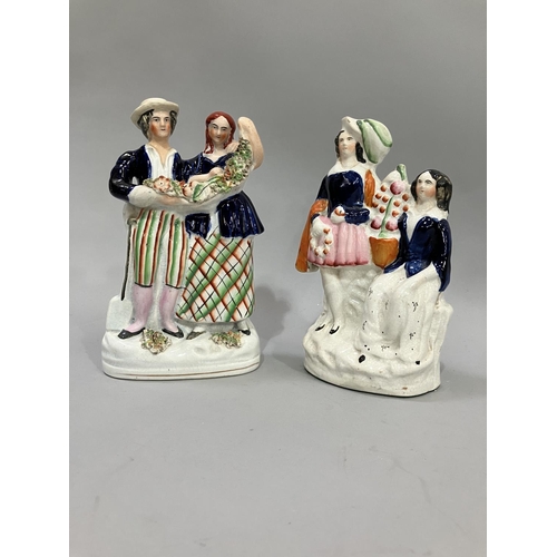 74 - Two 19th century Staffordshire figure groups, a male and female dressed in plaid holding a flower ga... 