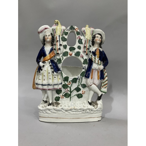 75 - A 19th century Staffordshire pocket watch stand, the apertures flanked by a male and female and bird... 