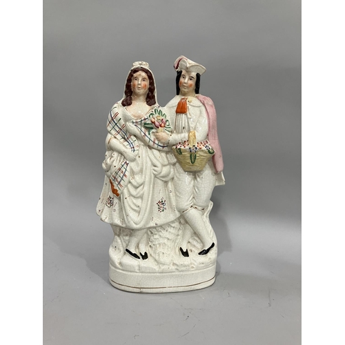 77 - A 19th century Staffordshire figure group of beau and his girl wearing a plaid shawl, he carrying a ... 