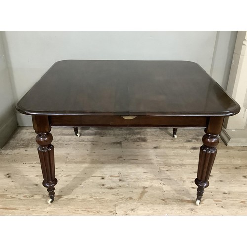 493 - A REPRODUCTION VICTORIAN MAHOGANY DINING TABLE on turned and reeded legs, brass caps and ceramic cas... 