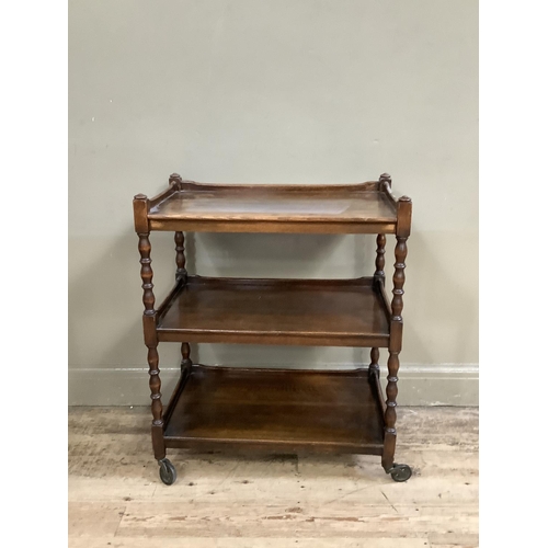 503 - An oak three tier tea trolley with turned uprights and legs on castors