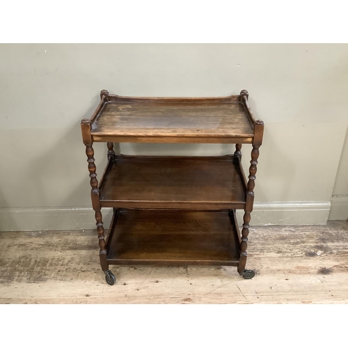 503 - An oak three tier tea trolley with turned uprights and legs on castors