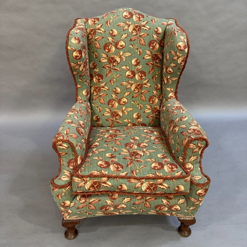 347 - A 1930s wing backed armchair reupholstered in fabric of deep pink and cream fruit on a pale green gr... 