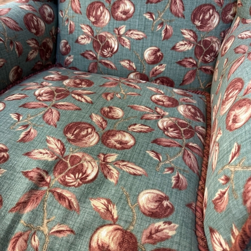 347 - A 1930s wing backed armchair reupholstered in fabric of deep pink and cream fruit on a pale green gr... 