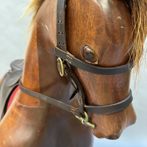 315 - A modern rocking horse with leather saddle, harness and reins, on planked rocking base, 190cm wide, ... 