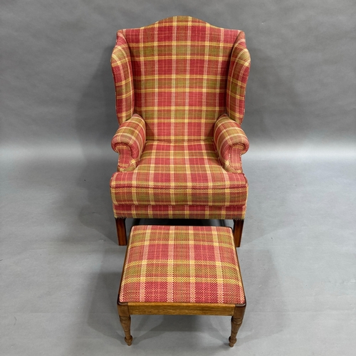 354 - An upholstered wing back armchair with low seat in cerise, olive green and cream check with foot sto... 