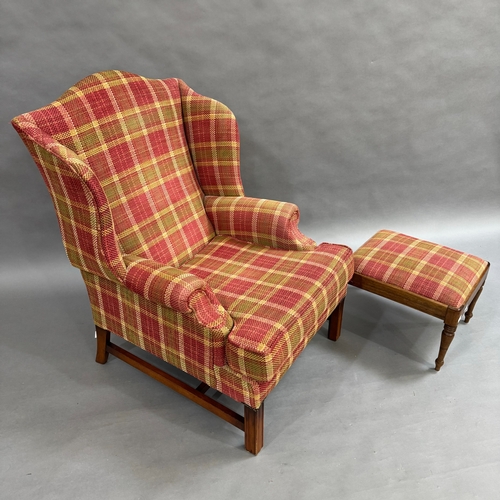 354 - An upholstered wing back armchair with low seat in cerise, olive green and cream check with foot sto... 