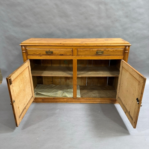 111 - A Victorian pine dresser base, two short drawers above two doors, turned pilasters to the sides, on ... 