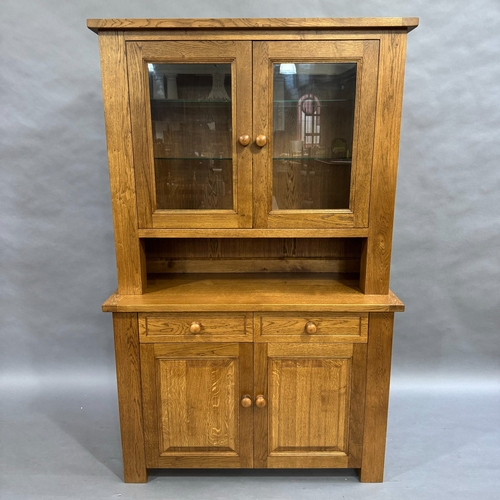 339 - A modern oak dresser, top comprising of two glazed doors opening to two glass shelves, base having t... 