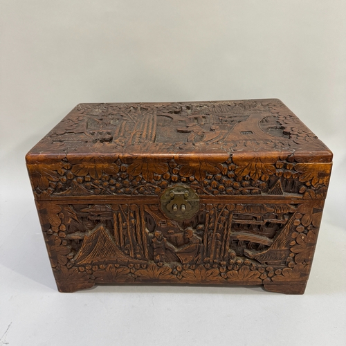 61 - A 1930s Chinese camphor wood chest of small proportions, all-over carved with figures in a garden la... 