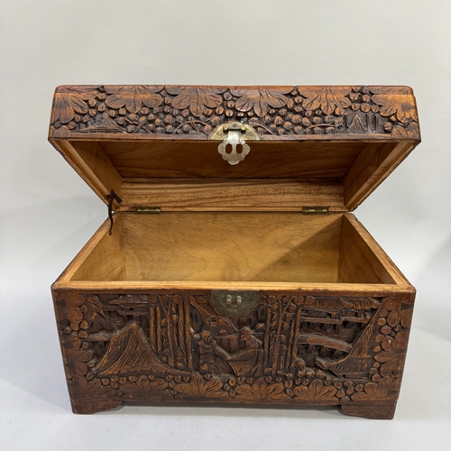 61 - A 1930s Chinese camphor wood chest of small proportions, all-over carved with figures in a garden la... 