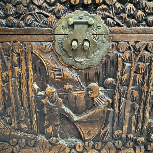 61 - A 1930s Chinese camphor wood chest of small proportions, all-over carved with figures in a garden la... 