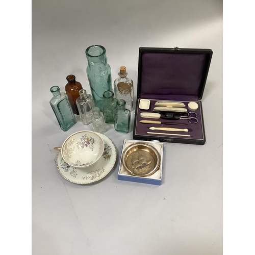 89 - A bone handled sewing set in case, several glass bottles, a continental cup and saucer and a commemo... 