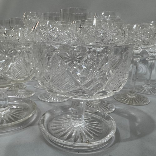 27 - A suite of cut table glass comprising 12 Champagne coupes, eleven smaller coupes, seven ports, six l... 