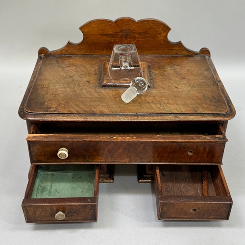 18 - A Victorian walnut miniature pedestal  desk, having a raised back, glass inkwell over one long and t... 