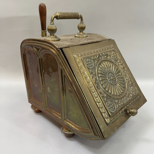 94 - A Victorian brass coal scuttle having a reeded handle, the hinged front embossed with a circular flo... 