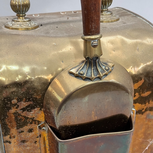 94 - A Victorian brass coal scuttle having a reeded handle, the hinged front embossed with a circular flo... 