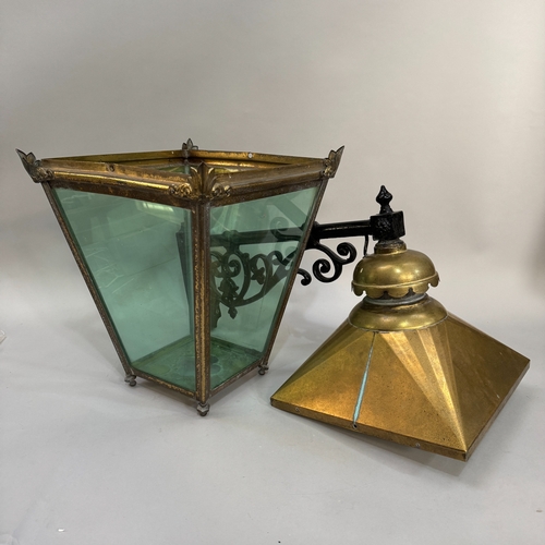 135 - A cast iron and brass exterior hanging lantern having a scroll work arm with scalloped inverted cup ... 