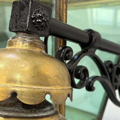 135 - A cast iron and brass exterior hanging lantern having a scroll work arm with scalloped inverted cup ... 