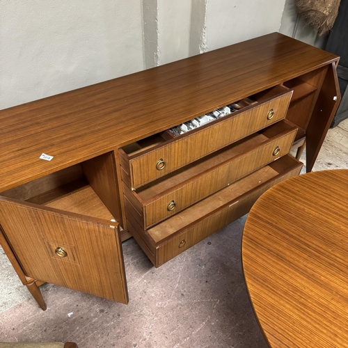 131 - A mid century teak dining suite comprising dining table and four chairs and a sideboard with two doo... 