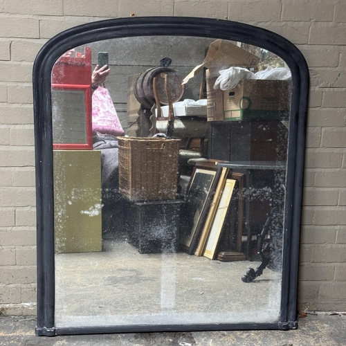 153 - An black painted over mantel mirror of arched profile, 136cm high x 113cm