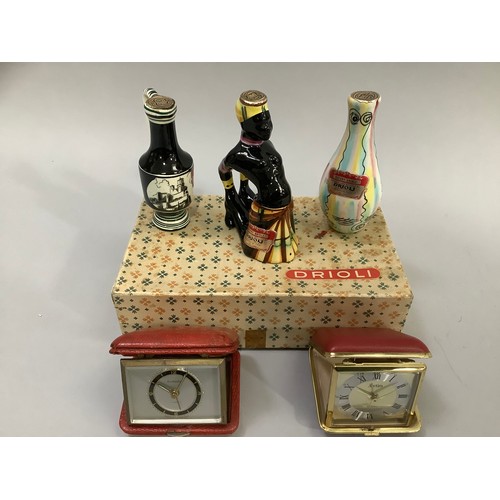 199 - Two travel clocks, three Orioli liqueur bottles in original box