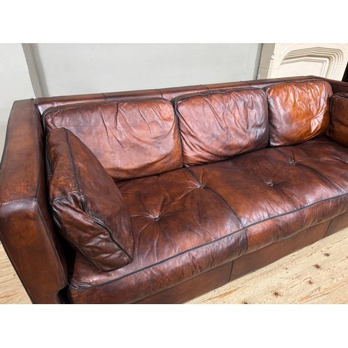 374 - A dark tan/brown leather three seater sofa with loose back and side cushions, 230cm x 98cm