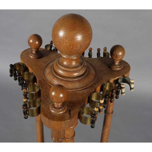 21 - AN EARLY 20TH CENTURY OAK CUE RACK with ball finial, with gilt metal, stained and natural bone clips... 