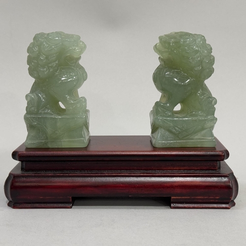 25 - A pair of carved jade-like Buddhist lions with rectangular plinth, lions 8cm high