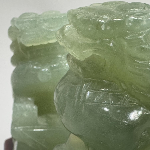 25 - A pair of carved jade-like Buddhist lions with rectangular plinth, lions 8cm high