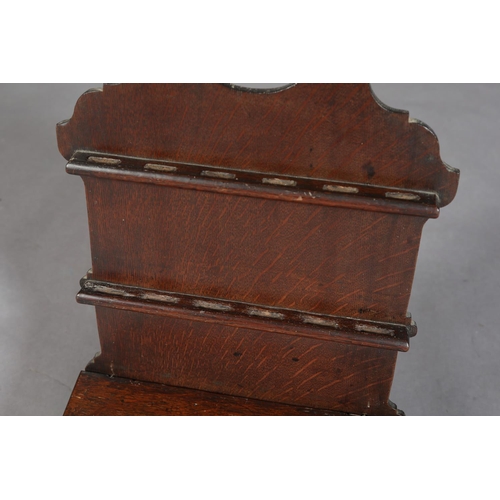 425 - AN EARLY 19TH CENTURY OAK SPOON RACK, having a shaped back with two rails above a box with slope top... 