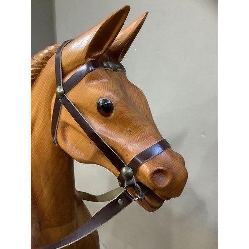 472 - A rocking horse in beech, carved mane, leather reins and saddle and on bow rocker